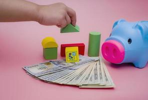 Hand of the kids take a wood block with small  house models on top of block.Concept of saving money for future , investment property and saving money to buy a house. On blur background. photo