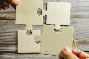 White jigsaw puzzle connecting together. Team business success partnership or teamwork concept. A group of business people assembling jigsaw puzzle. Business solutions, success and strategy concept. photo