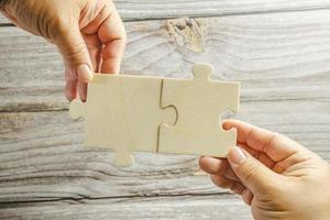 White jigsaw puzzle connecting together. Team business success partnership or teamwork concept. A group of business people assembling jigsaw puzzle. Business solutions, success and strategy concept. photo