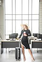 Tourist concept, Caucasian beautiful business woman with blue eye long hair hold the passport, air ticket, luggage and hat in the office prepare travel accessories for travelling in summer holiday photo