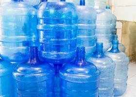 botellas de plástico azul o galones azules de agua potable se apilan en la fábrica de agua potable para hacer circular el concepto de negocio de fábrica de agua potable. foto