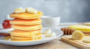 Stack of  banana pancakes with slices of fresh bananas, a Sweet Homemade Stack of Pancakes with Butter and Syrup for Breakfast in wooden background photo