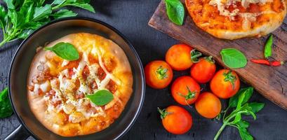 Top view of home made pizza, vegetables, ingredients on a Black wooden  background. Pizza is cooking in the pan. Pizza photo