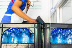 Close-up of a blue water bottle being packaged as a drinking water product in a factory where a worker produces drinking water in a clean drinking water plant  clean drinking water production business photo