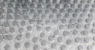 una gran cantidad de productos de agua embotellada de plástico en una planta de agua potable que están dispuestos en fila esperando ser vendidos a los supermercados. negocio de bebidas y agua potable. foto