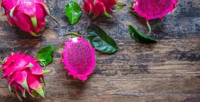 la vista superior de la fruta del dragón rojo en rodajas medias del género hylocereus pertenece a la familia cactaceae, que es la misma familia que el cactus sobre fondo de madera foto