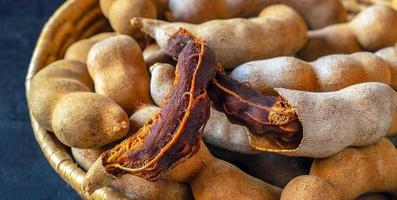 primer plano de una deliciosa vaina de tamarindo maduro con tamarindo seco en una canasta foto