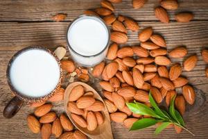 leche de almendras y nueces de almendras fondo de madera, deliciosas almendras dulces en la mesa, nueces de almendras tostadas para comida saludable y bocadillos foto