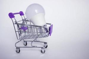 Mini decorative shopping cart with LED lamp on white background with copy space photo