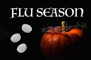Flu season, orange pumpkin with barbed wire wreath on black background. Medical awareness poster. photo