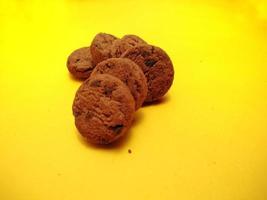 mini galletas con trocitos de chocolate sobre fondo amarillo. para fondos, portadas, pancartas y más. foto