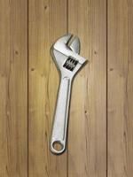metal adjustable wrenches on a brown wooden background, top view photo