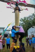 blitar, indonesia - 11 de septiembre de 2022. amas de casa participando en un concurso de escalada de árboles de plátano para conmemorar el día de la independencia de indonesia por la tarde en blitar foto