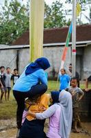 blitar, indonesia - 11 de septiembre de 2022. amas de casa que participan en un concurso de escalada de árboles de plátano para conmemorar el día de la independencia de Indonesia por la tarde en blitar foto