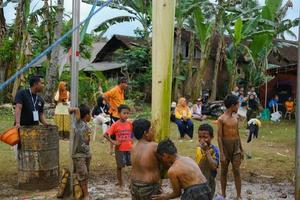 blitar, indonesia - 11 de septiembre de 2022. varios niños pequeños que trabajan juntos participan en un concurso de escalada de árboles de plátano para conmemorar la independencia de Indonesia en blitar foto