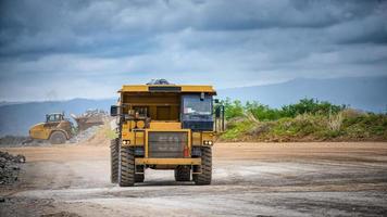 Work of trucks and the excavator in an open pit on gold mining photo