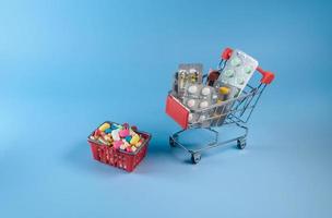 Buy medicine. Shopping basket with various medicinal, pills, tablets on blue background. Studio Photo