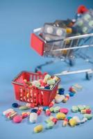 Buy medicine. Shopping basket with various medicinal, pills, tablets on blue background. Studio Photo