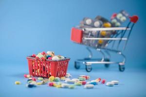 Buy medicine. Shopping basket with various medicinal, pills, tablets on blue background. Studio Photo