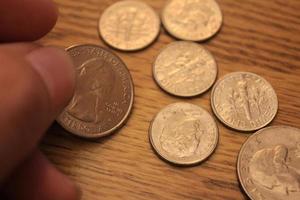 hand picking up a quarter coin in american currency spread on the wooden floor photo