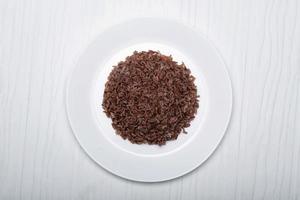 comida asiática cocida arroz rojo en plato aislado sobre fondo de madera blanca. foto