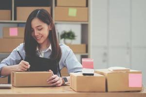 Retrato de mujer joven asiática SM trabajando con una caja en casa el lugar de trabajo.Propietario de una pequeña empresa de inicio, pequeña empresa emprendedora o empresa independiente en línea y concepto de entrega. foto