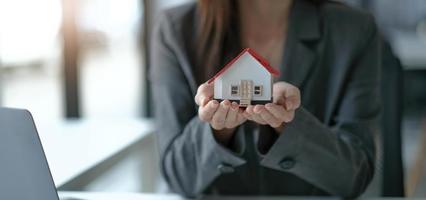 architecture, building, construction, real estate and property concept - close up of hands holding house or home model photo