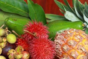 Lot of of ripe fruits with ripe pineapple on wooden background photo
