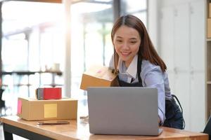 Portrait of Asian young woman SME working with a box at home the workplace.start-up small business owner, small business entrepreneur SME or freelance business online and delivery concept. photo