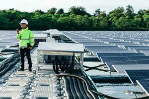 el retrato de un joven ingeniero comprueba los paneles solares fotovoltaicos. concepto. servicio de electricidad de tecnología de energía renovable, energía verde. foto