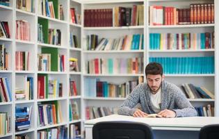 portrait of student while reading book  in school library photo