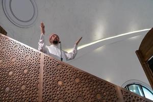 el joven imán árabe musulmán tiene un discurso en la oración del viernes por la tarde en la mezquita. foto