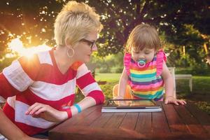 mom and her little daughter using tablet computer photo