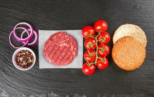 The raw ingredients for the homemade burger on black slate background. Top view. photo