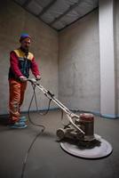 worker performing and polishing sand and cement screed floor photo