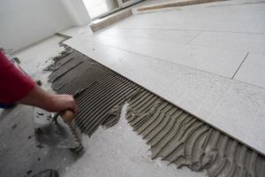 worker installing the ceramic wood effect tiles on the floor photo