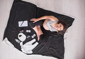 top view of pregnant woman checking list of baby clothes photo