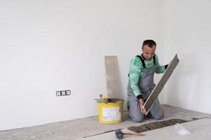 worker installing the ceramic wood effect tiles on the floor photo