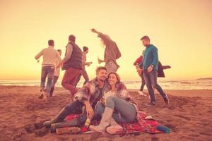 pareja disfrutando con amigos al atardecer en la playa foto