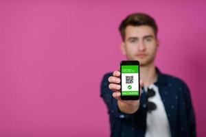 covid passport, a young man shows his code and covid passport on his cell phone photo