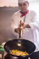 chef volteando verduras en wok foto