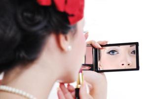 beautiful young woman applying makeup photo