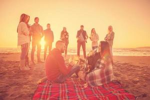 Couple enjoying with friends at sunset on the beach photo