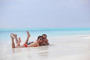 feliz pareja joven divertirse en la playa foto