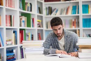 portrait of student while reading book  in school library photo