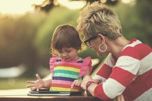 mom and her little daughter using tablet computer photo