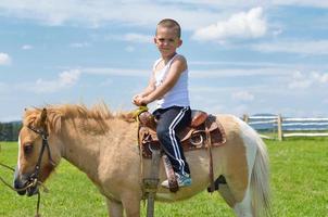 niño montar pony foto