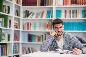 portrait of student while reading book  in school library photo