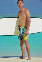 Man with surf board on beach photo