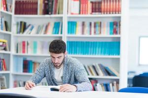 portrait of student while reading book  in school library photo